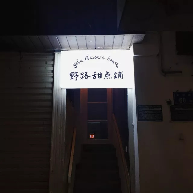 小小的一块白底黑字霓虹灯招牌挂在一家旧式理发店旁,走上一条窄窄的